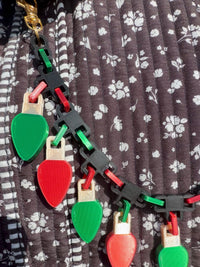 Close-up of the Christmas lights bag chain: silk red and green links, black connectors and C9 style bulbs